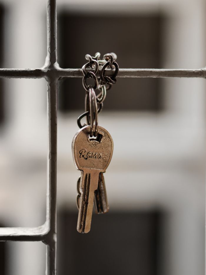 about-us A detailed shot of metal keys hanging on a wire grid with soft focus background.